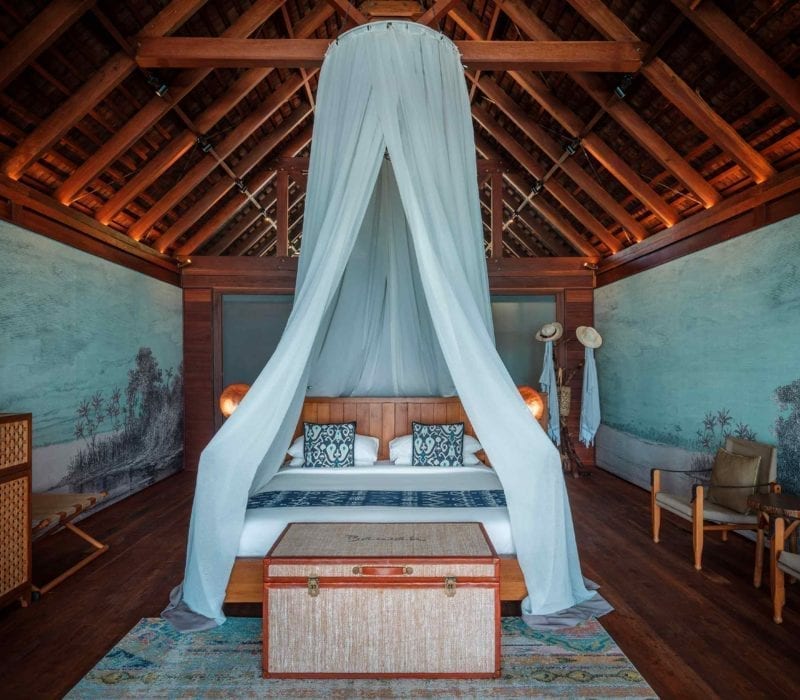 Overwater Bungalow bedroom with beautiful wall art and canopied bed, Bawah Reserve, Indonesia