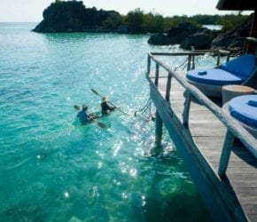 Couple kayaking with a transparent kayak in the crystal clear lagoons at Bawah Reserve, Indonesia