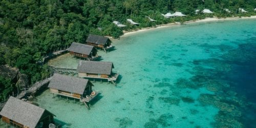 Overwater bungalows and beach suites with turquoise water view at Bawah Reserve, Indonesia.
