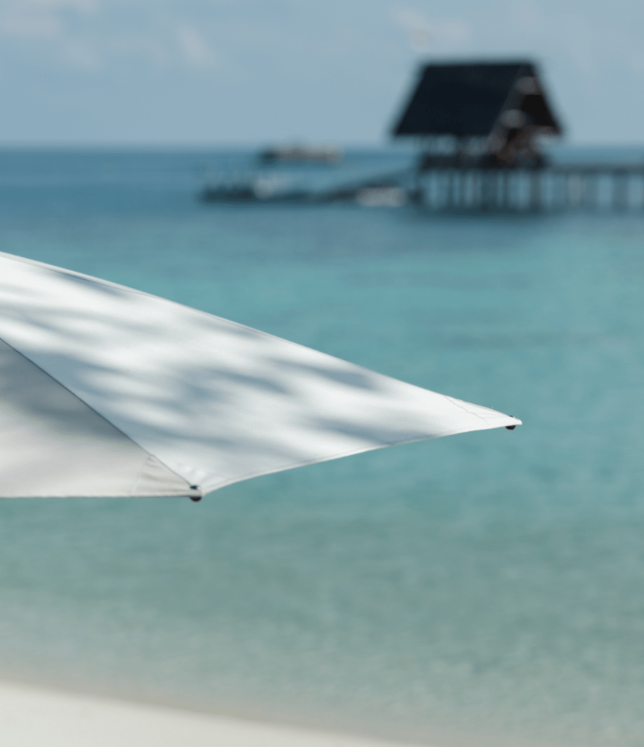 Bawah Reserve, Indonesia, private island hotel and resort, 13 private beaches. umbrella on the beach overlooking the jetty.