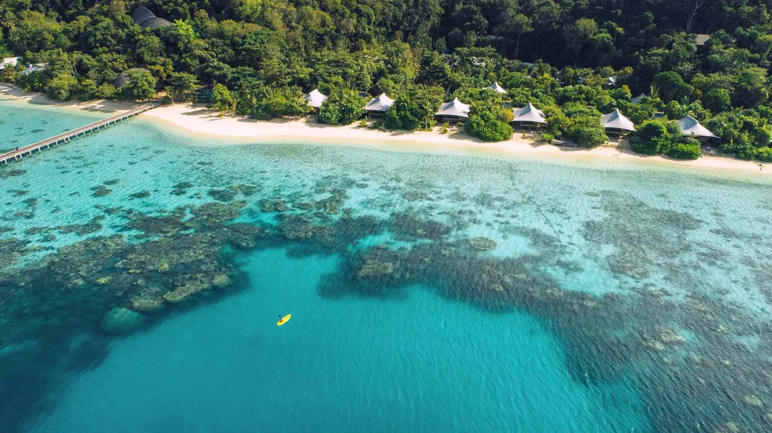 Bawah Reserve, private island, beach resort and hotel, Indonesia. Kayaking in the lagoon. Tented beach suites line the shore.