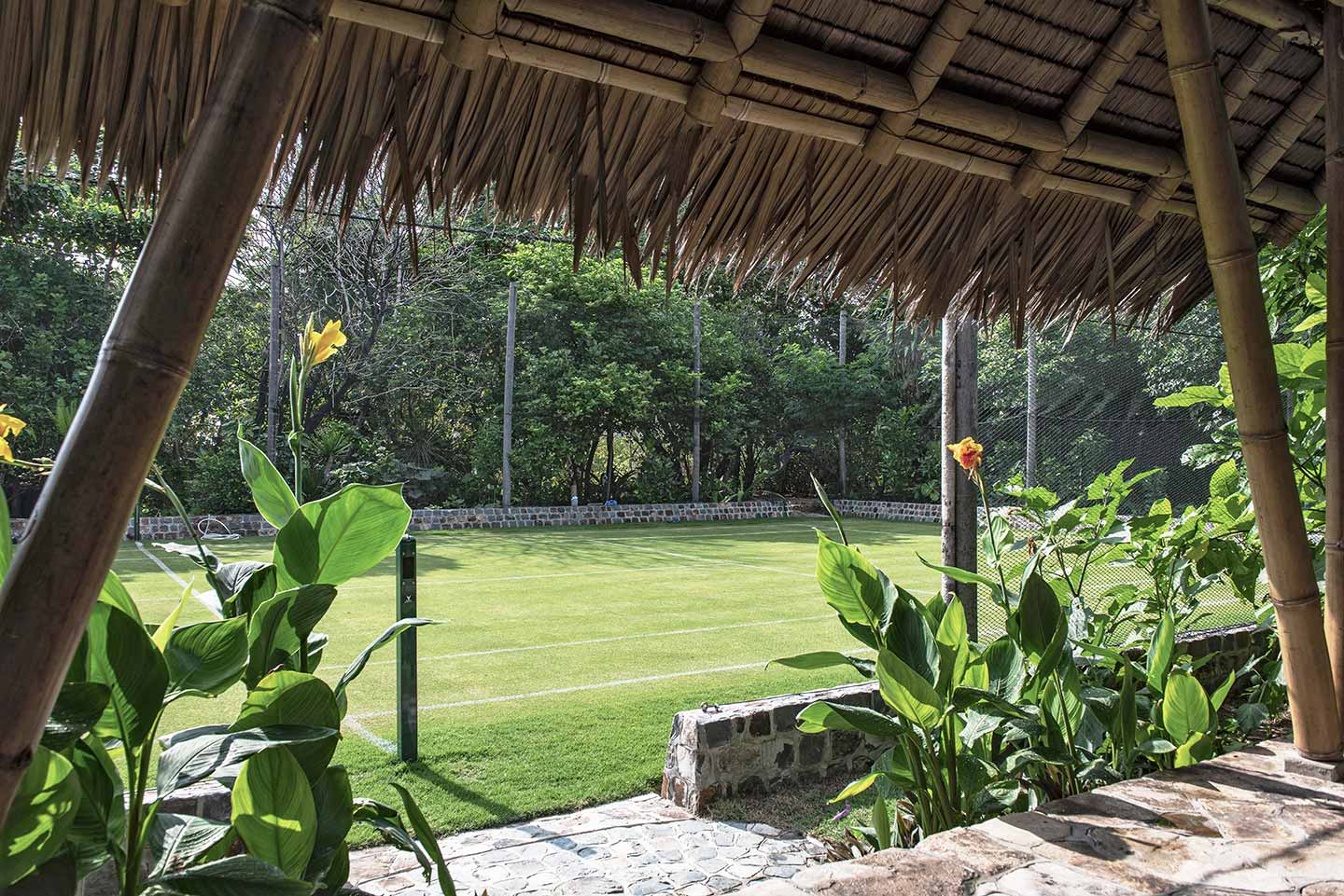 Private island tennis court. Bawah Reserve hotel and resort grass outdoor tennis court on Elang.