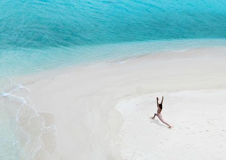 solo girl doing yoga pose on beach with blue ocean in front